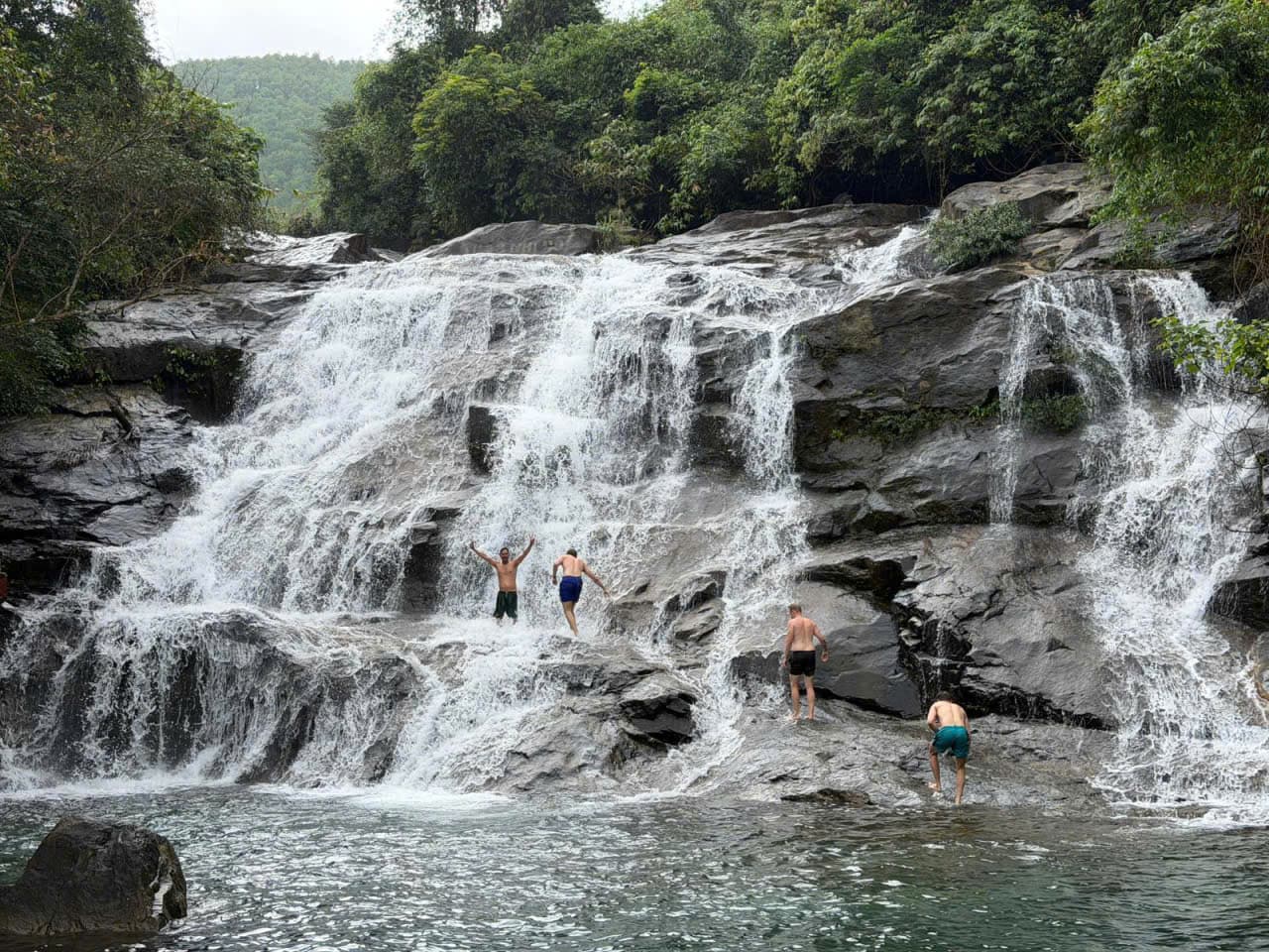 Four riders standing in the cascade at Elephant Springs waterfall