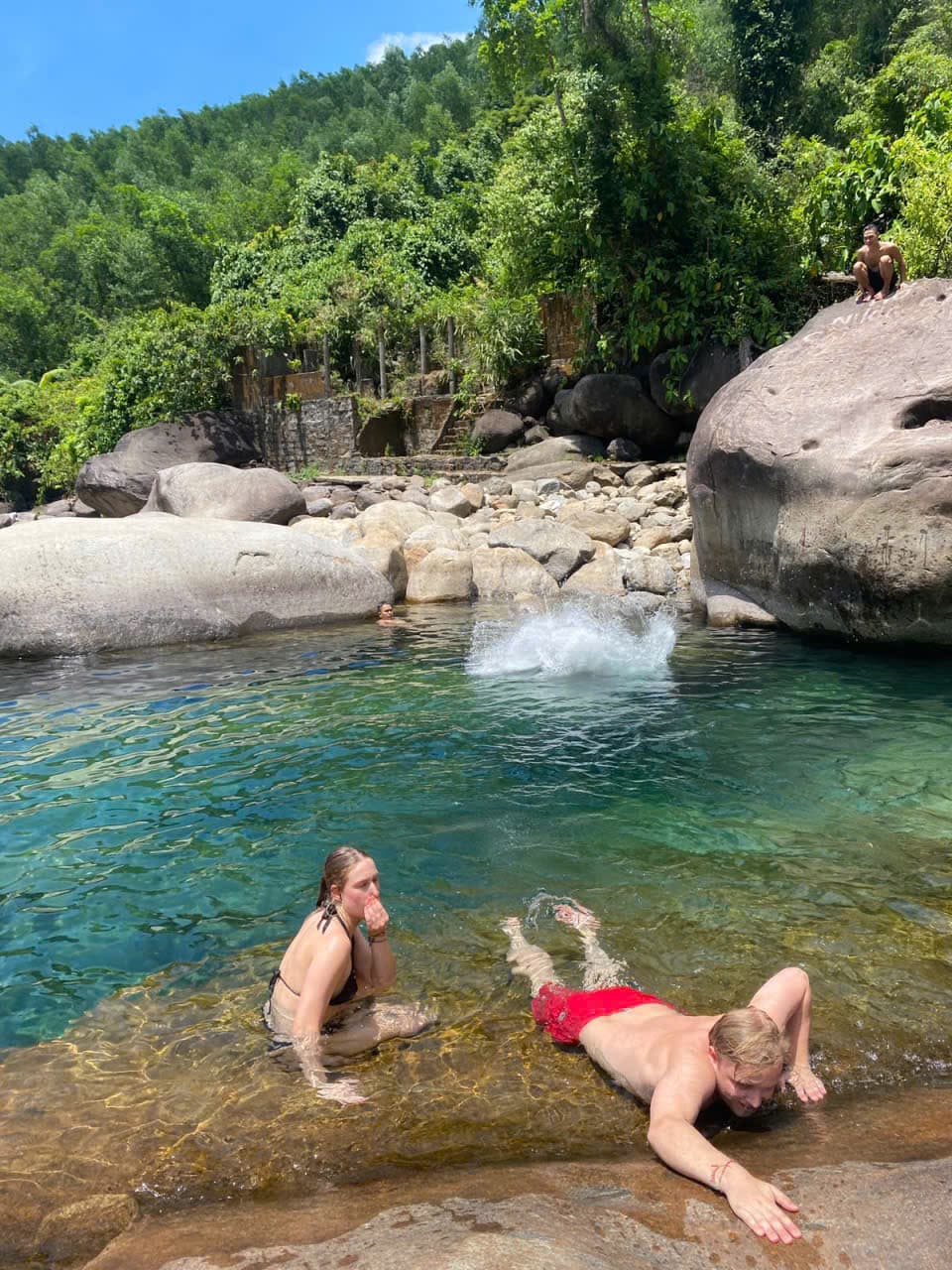 Swimmers in the clear emerald pool below the falls