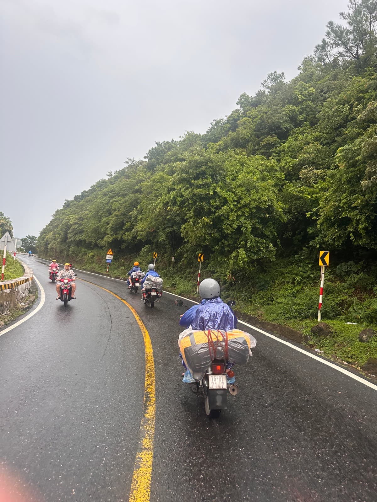Riders in rain ponchos following the curve of the pass in the rain